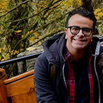 Manuel Castro sits outside while wearing a jacket and smiling