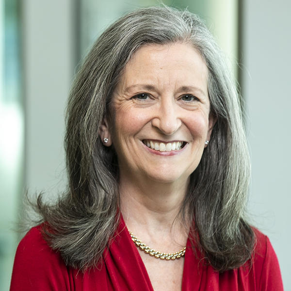 Bonnie Stabile stands smiling while wearing a red dress